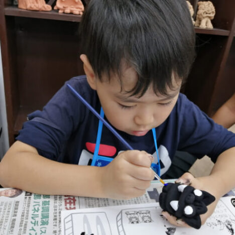 シーサーの絵付けをしている男の子